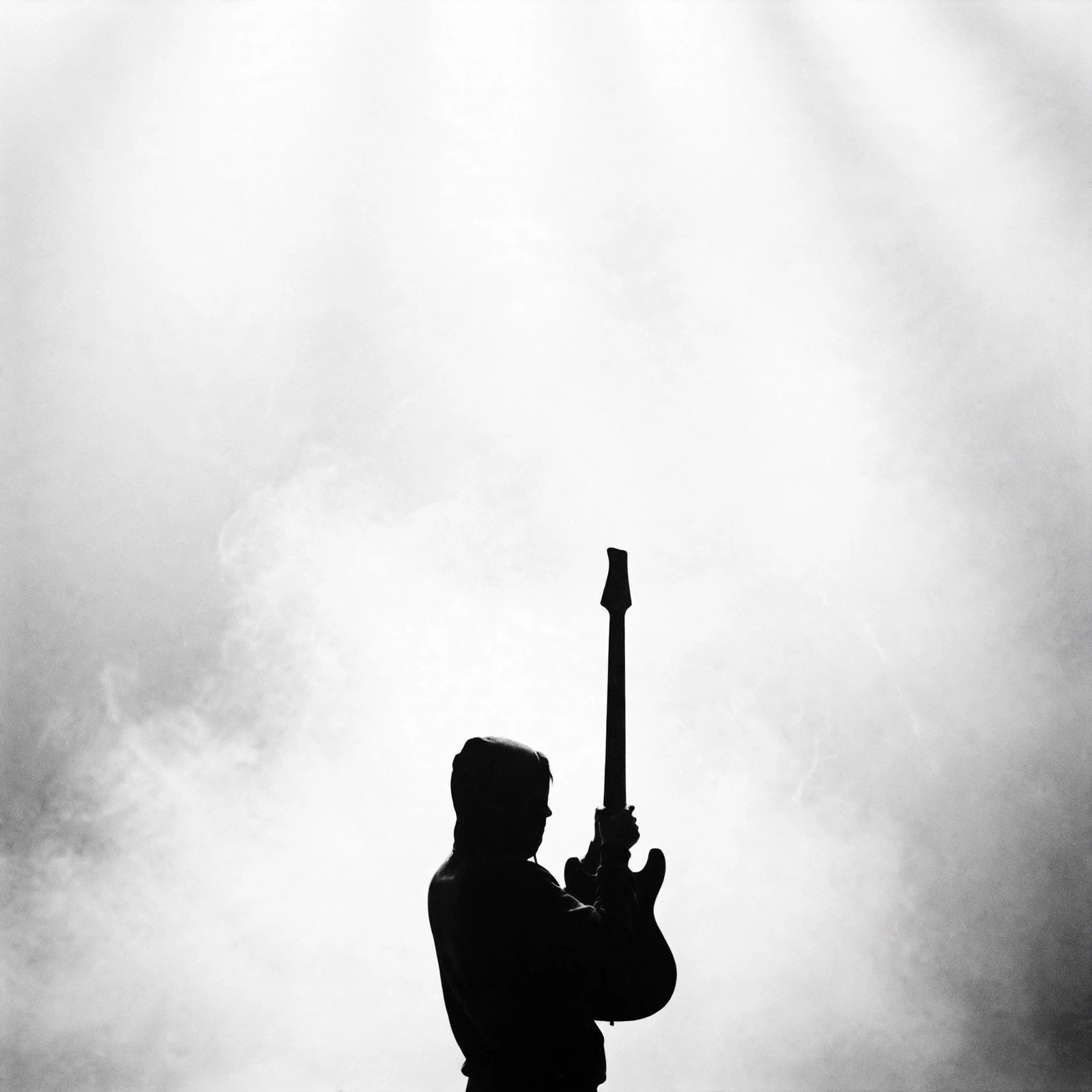 Guitarist in silhouette against a white wall of light